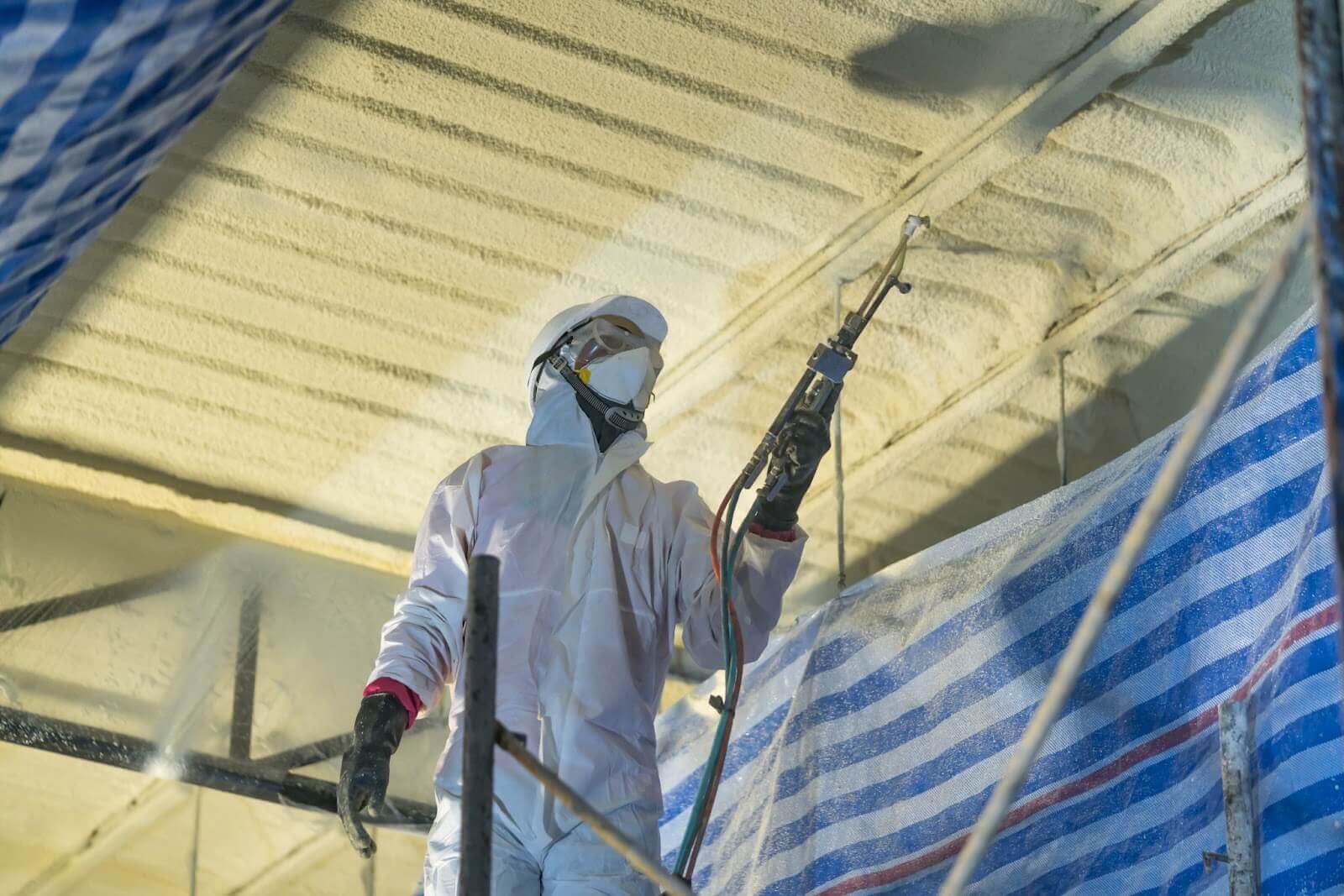Technician spraying foam on ceiling of building
